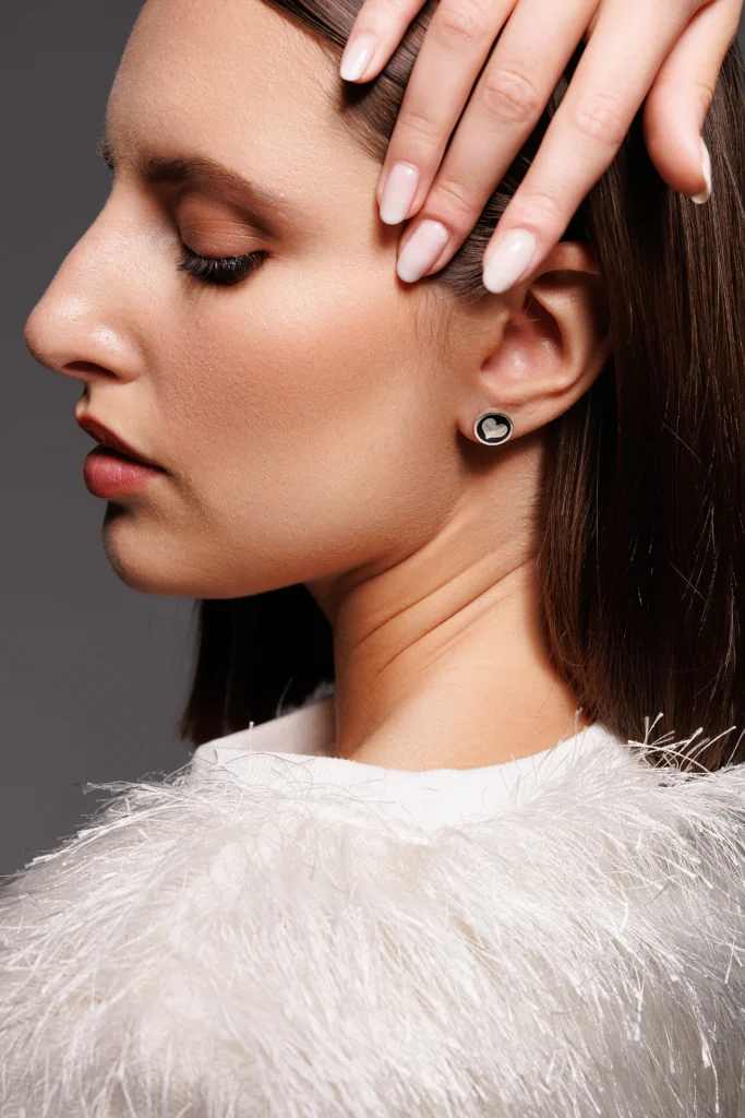 Close-up dell’orecchio della modella con Orecchino Round Cuore in Argento 925 con smalto nero, un gioiello dal design essenziale e romantico.