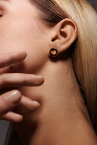 Primo piano di una modella con l'Orecchino Round Cuore Nero in Argento 925, enfatizzando il design e la brillantezza dello smalto nero.