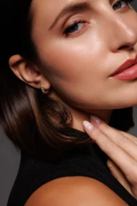Close-up dell’orecchio con Orecchini a cerchio con brillanti multicolor, placcati oro giallo, per un look luminoso e ricco di colore.